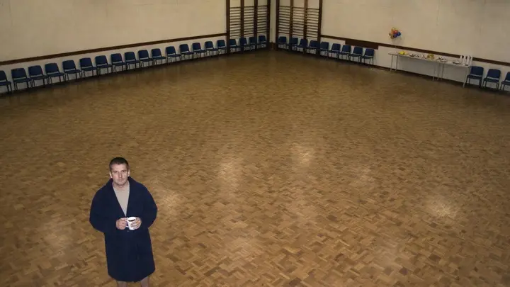 A man alone in the middle of an empty village hall